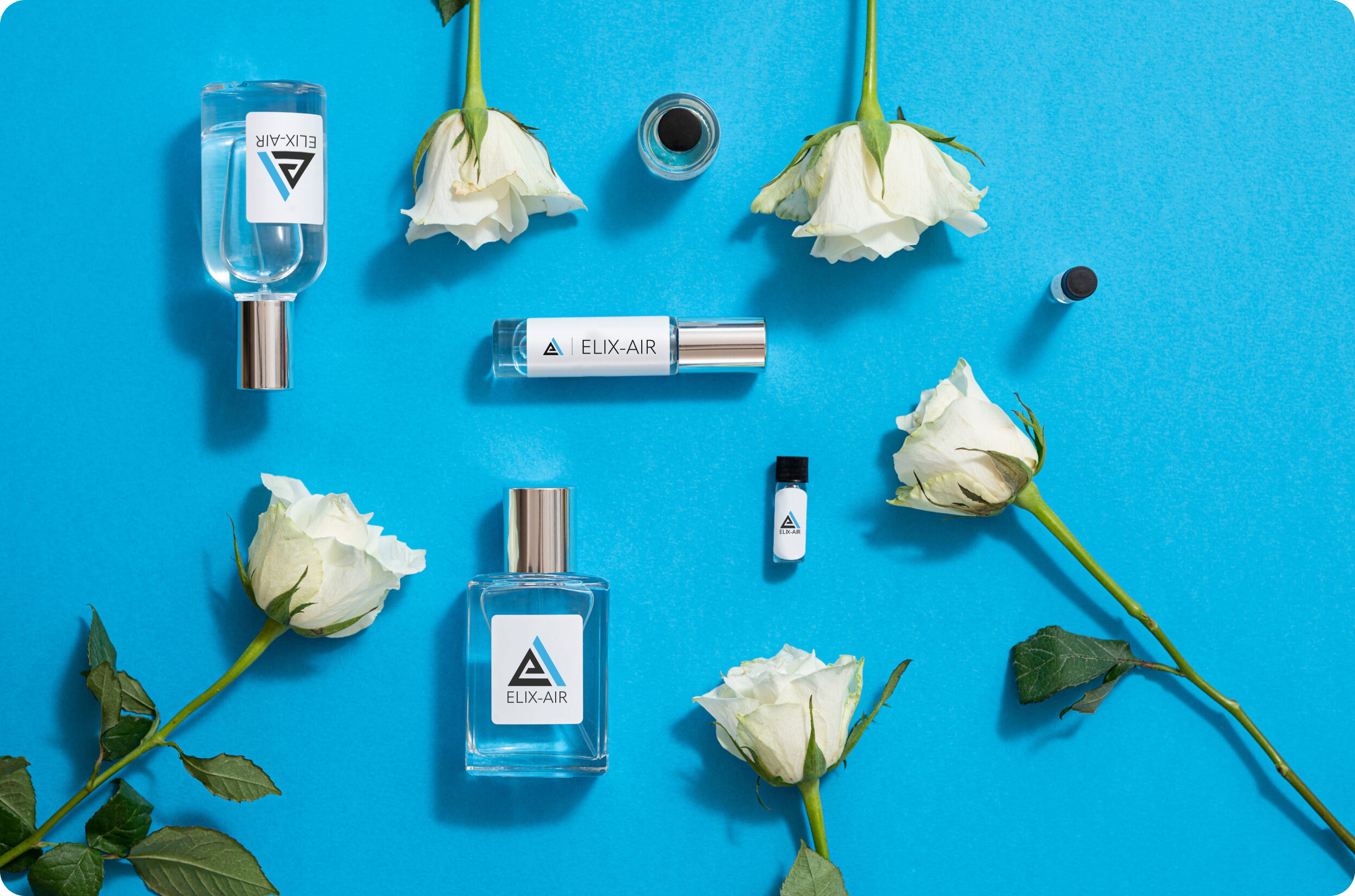 Collection of perfume bottles on a blue background surrounded by single rose flowers