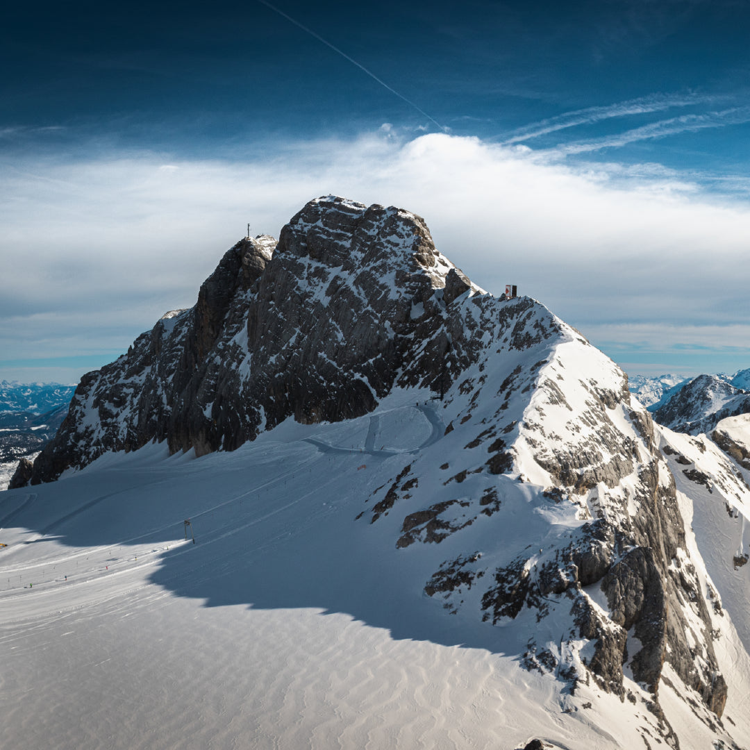 A cold looking picture of a Mountain Summit with wispy clouds and blue skies