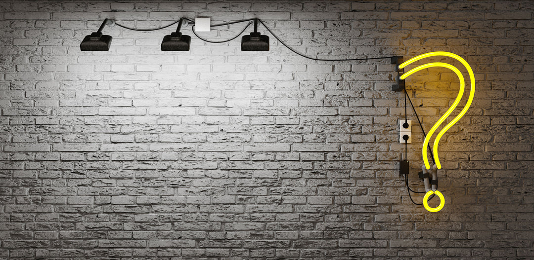 Grey brick wall with spotlight and a yellow neon light question mark